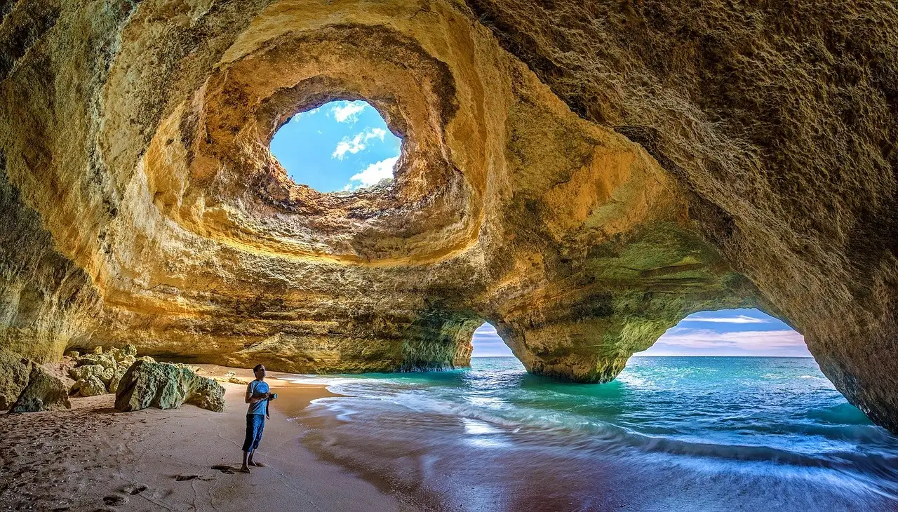 Inside the Benagil sea cave, with light streaming through the round opening in its golden roof
