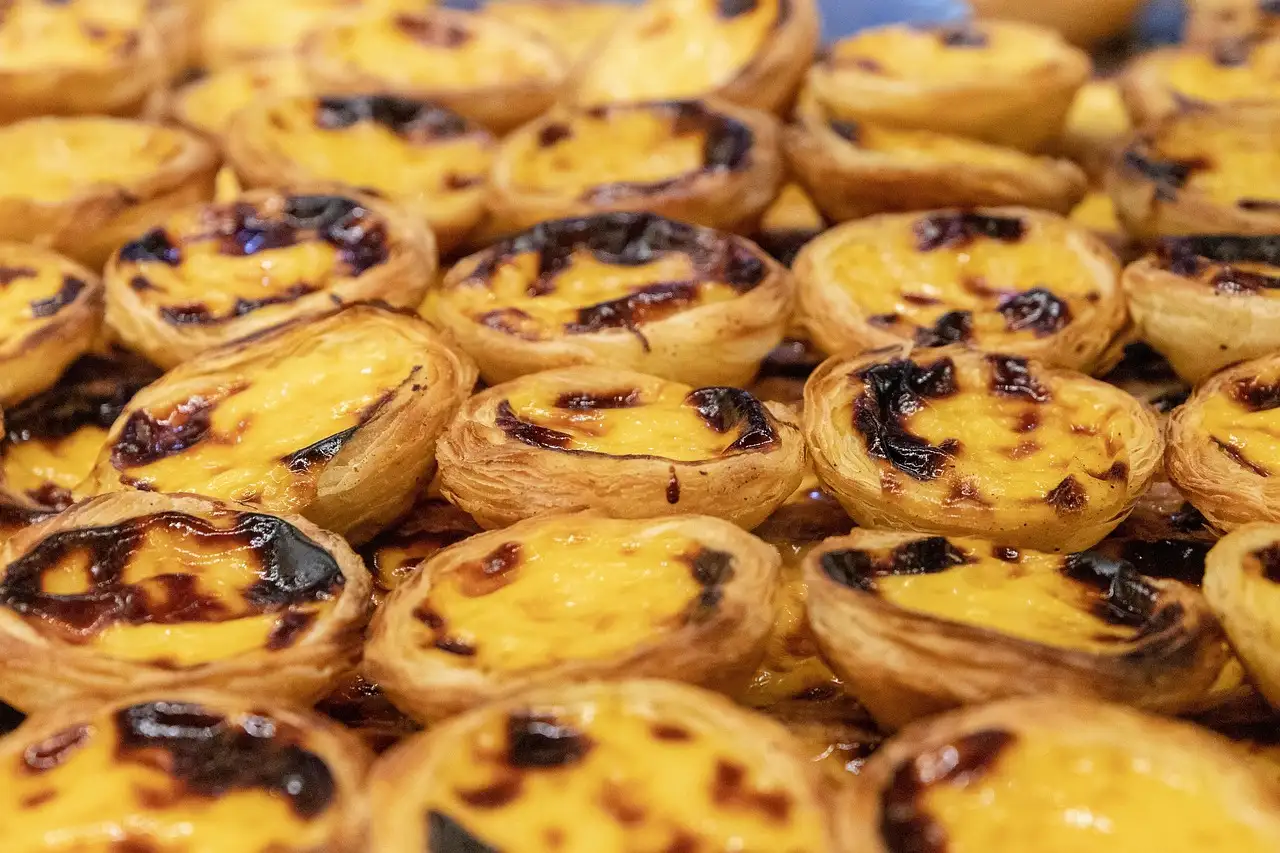 Close-up of freshly baked pastéis de nata with caramelised tops, packed on a baking tray