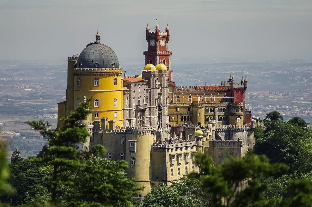 Pena Palace's yellow dome and red tower above the pine forest, with the plain far below
