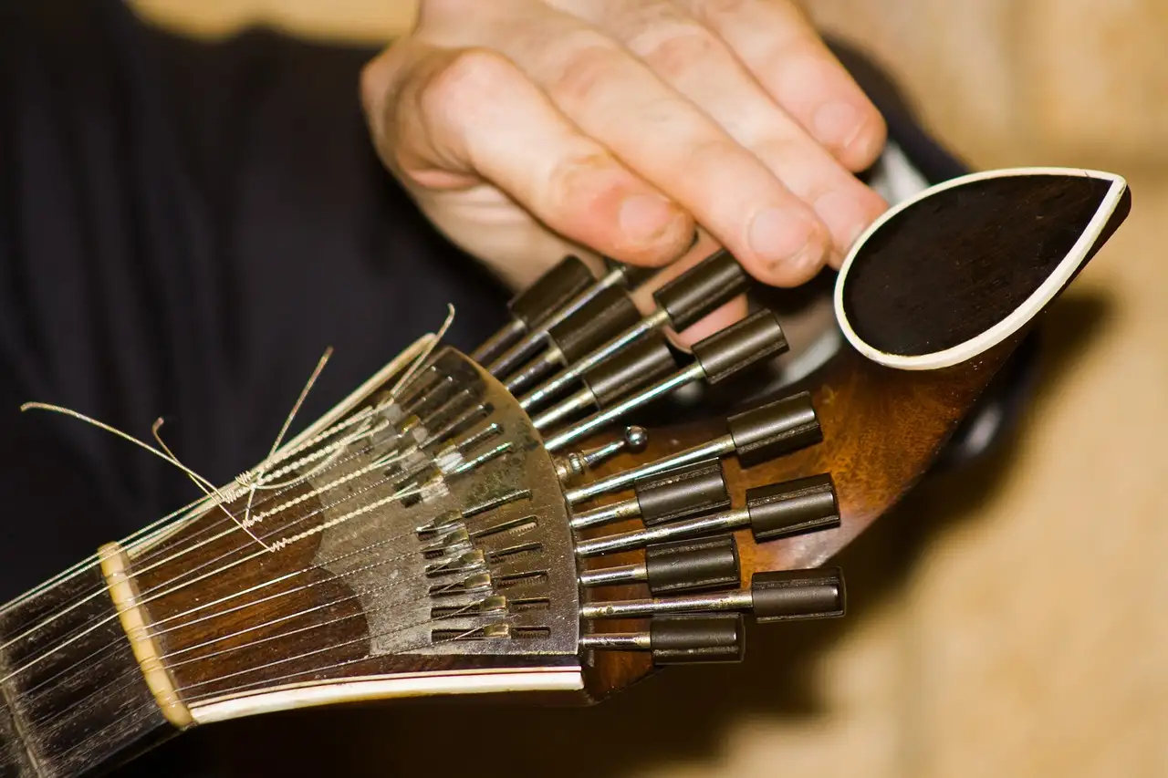 A hand tuning a Portuguese guitar, the instrument of fado, in warm low light