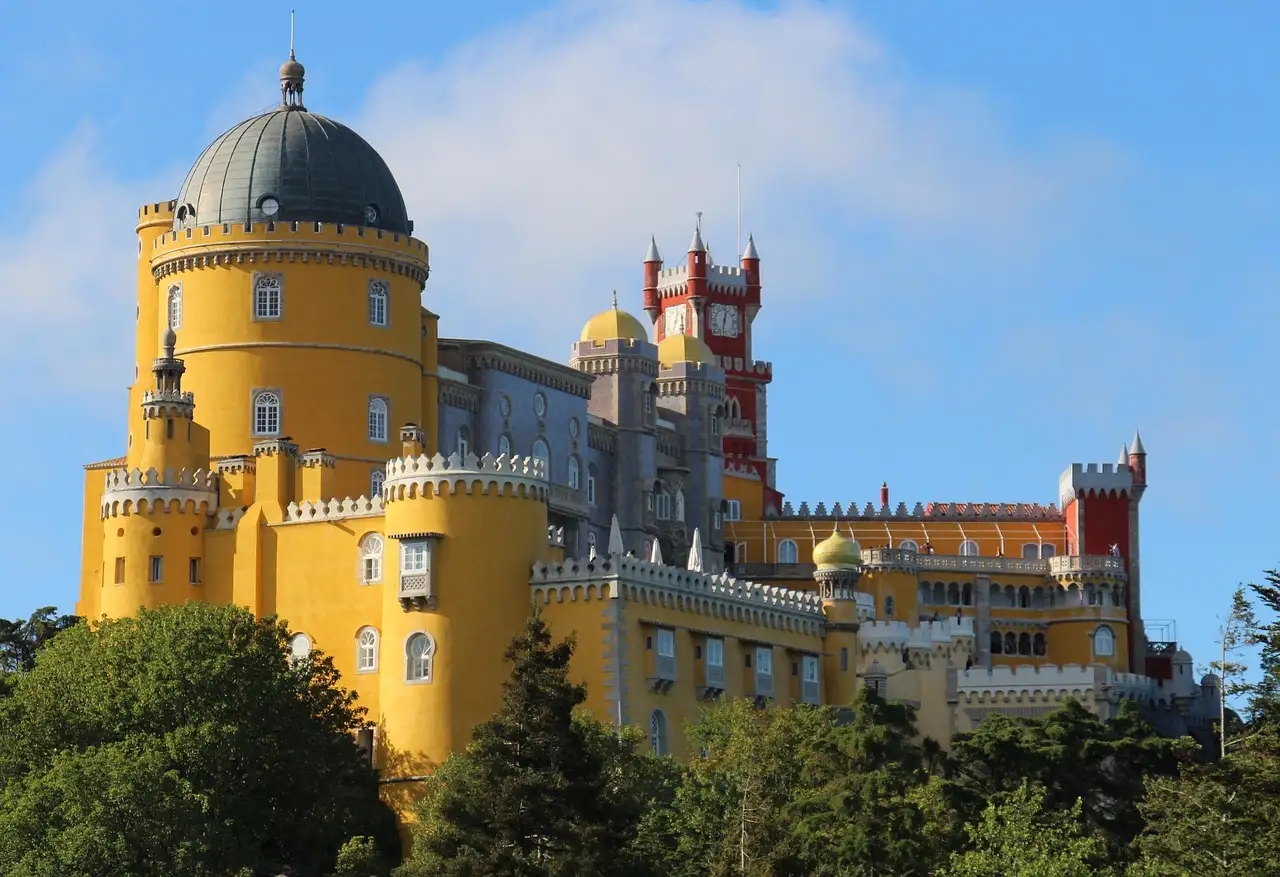 Pena Palace in Sintra with its yellow tower and red battlements against a blue sky
