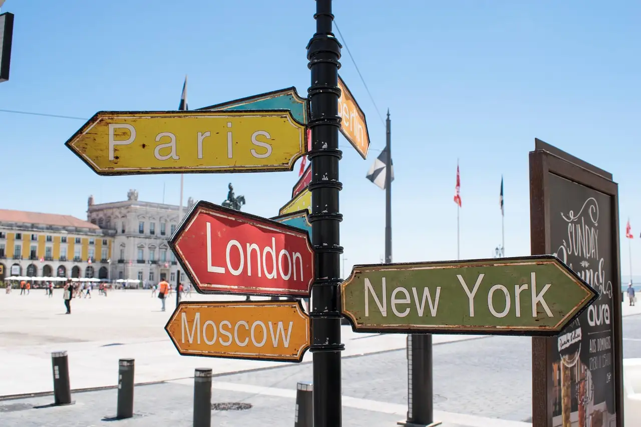 A signpost with arrows pointing to Paris, London, New York and Moscow on a sunny square in Lisbon