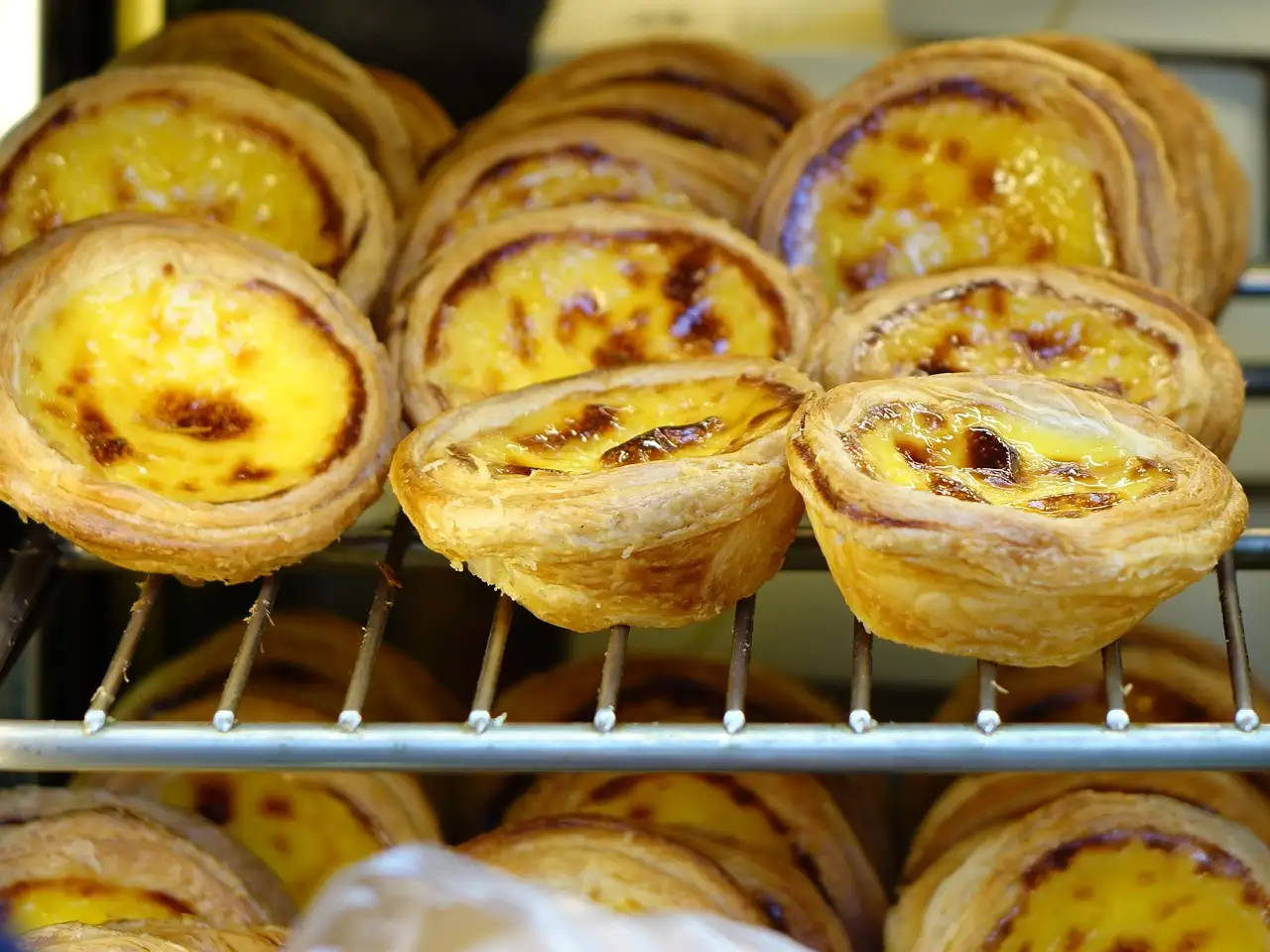 Egg custard tarts stacked on a bakery rack, close-up