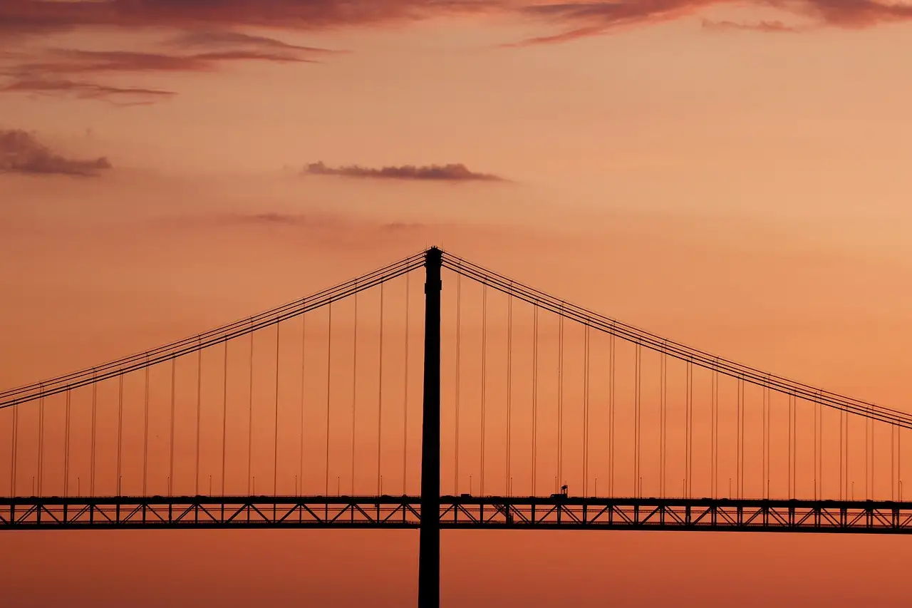 25 de Abril Bridge silhouetted against an orange sunset sky over the Tagus in Lisbon