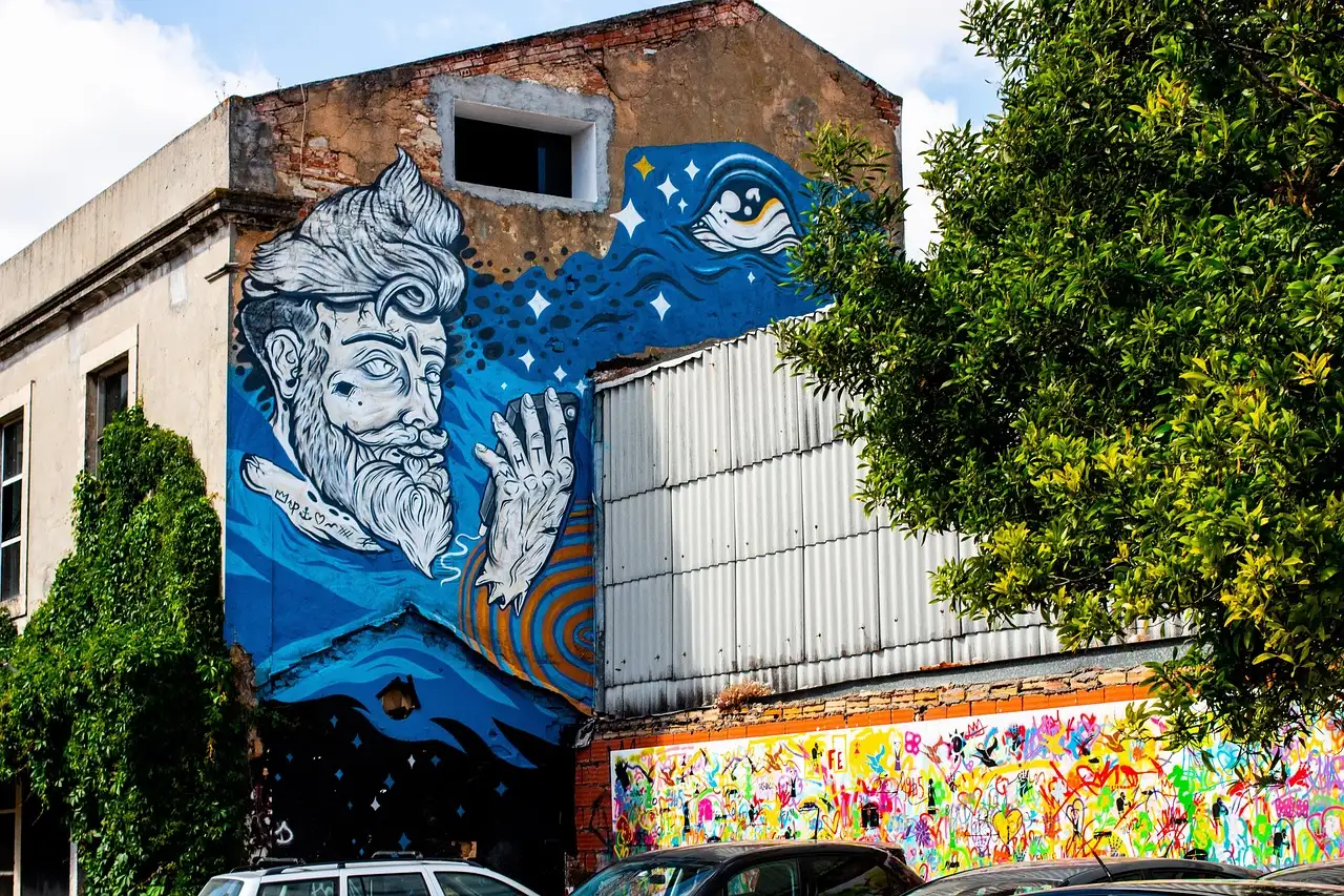 Large blue mural of a bearded face on a wall at LX Factory in Lisbon