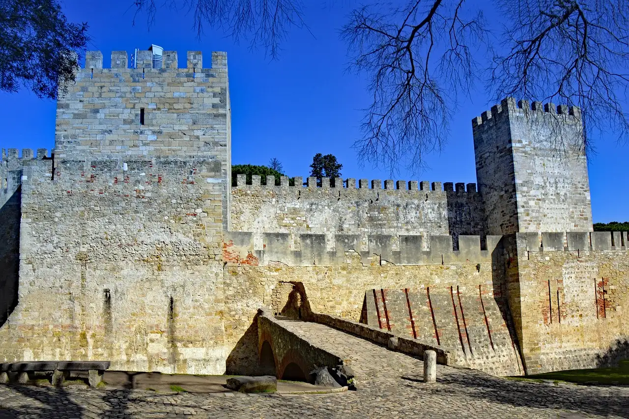 Crenellated walls and square towers of São Jorge Castle in Lisbon under a blue sky