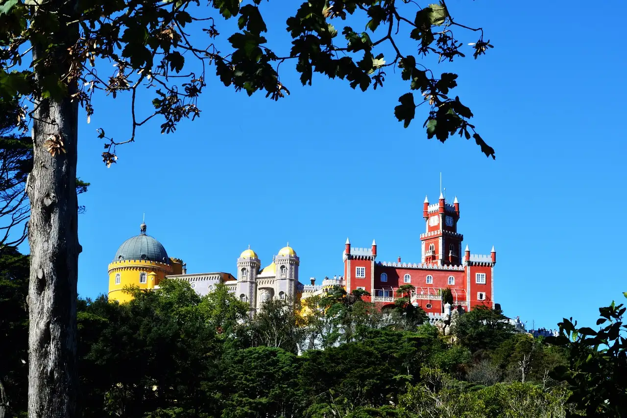 Pena Palace's yellow dome and red tower seen through the pine forest of Sintra
