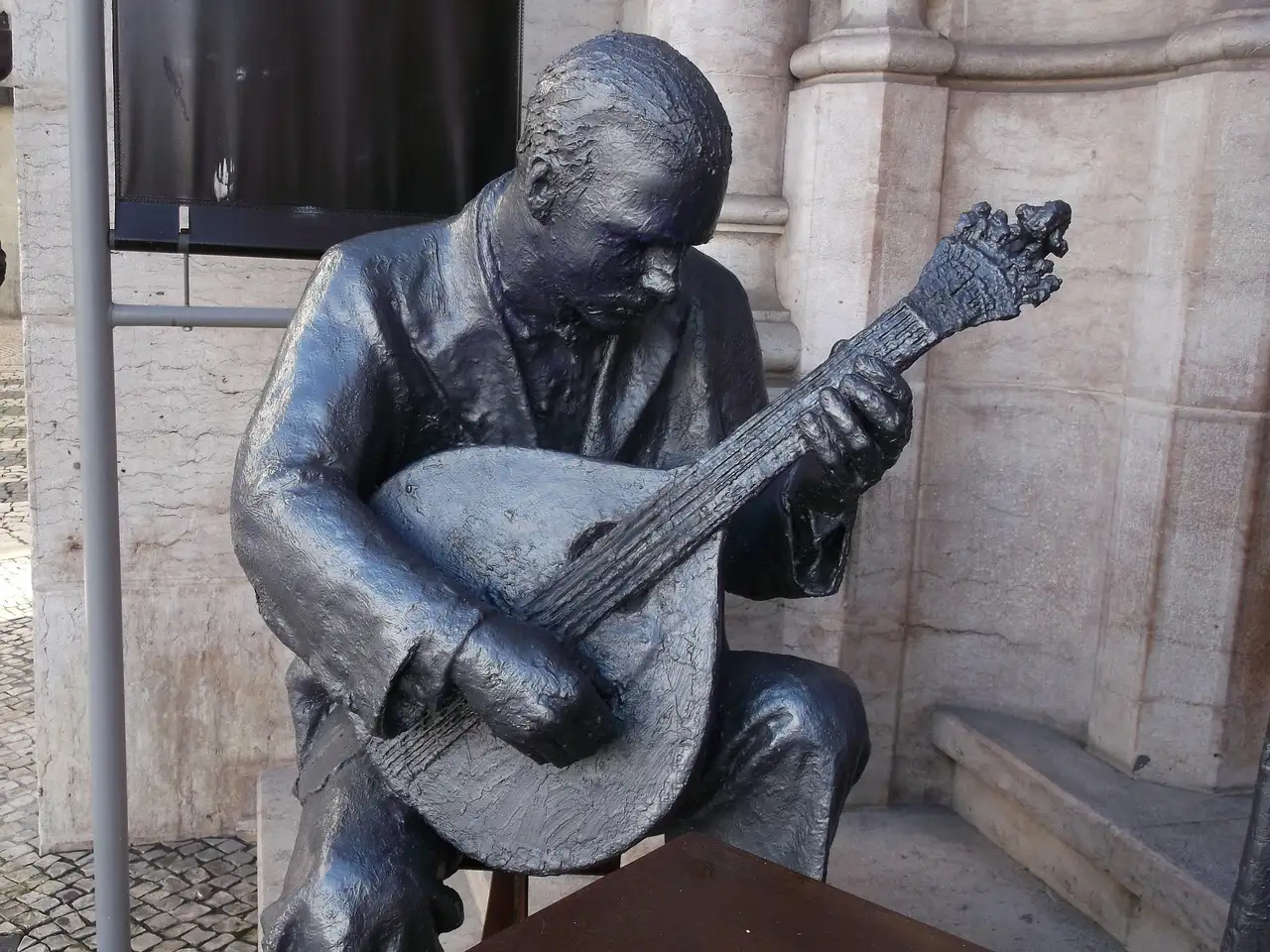 Bronze statue of a fado musician playing a Portuguese guitar in Lisbon