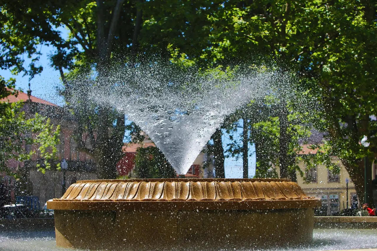 A fountain spraying water in a tree-lined Lisbon square