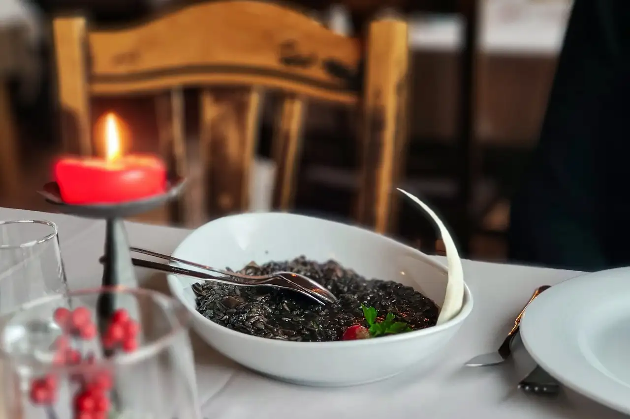 Candlelit restaurant table at night with a bowl of food and glasses